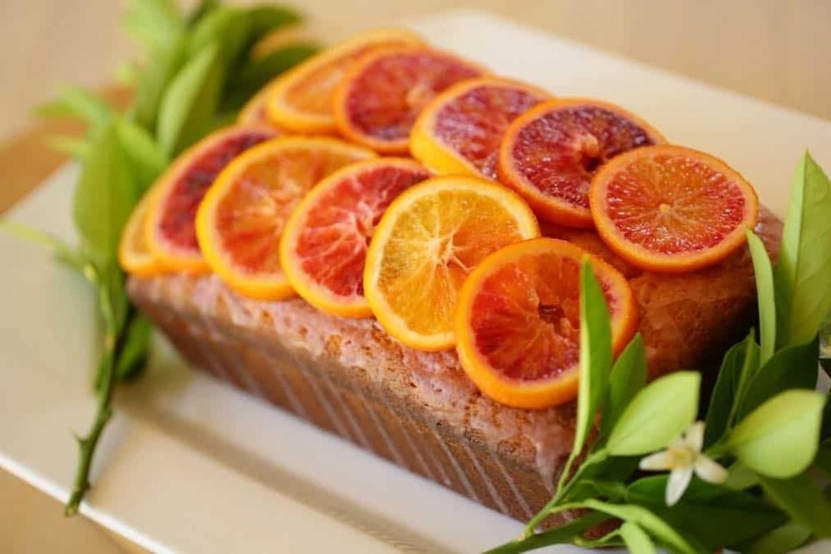 A blood orange cake, garnished with citrus leaves.
