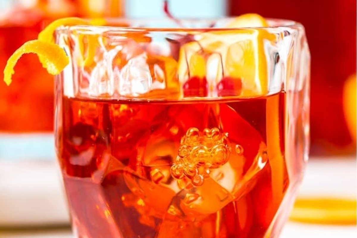 A glass of a red drink with orange slices and ice, perfect for St. Patrick's drinks.