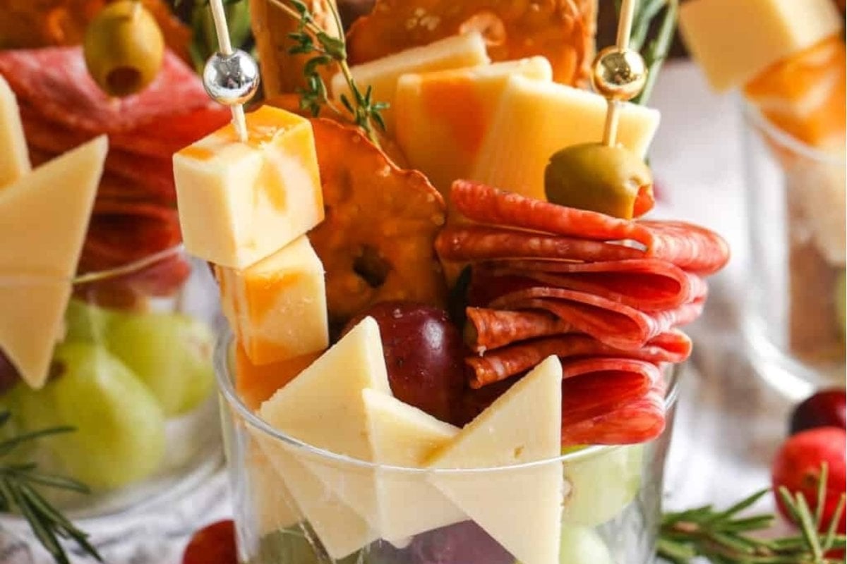 A tray of cheese and fruit for a girl's dinner in a glass vase.
