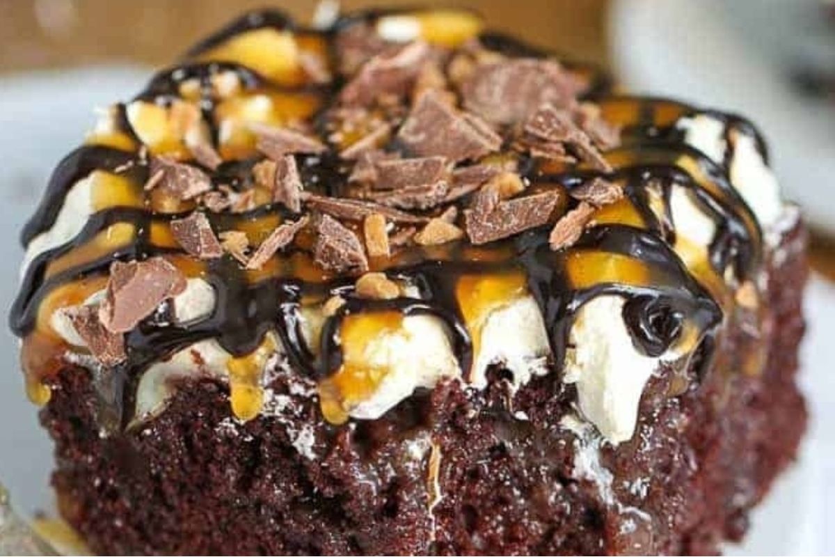 Decadent chocolate cake topped with whipped cream, caramel, chocolate syrup, and chocolate shavings.