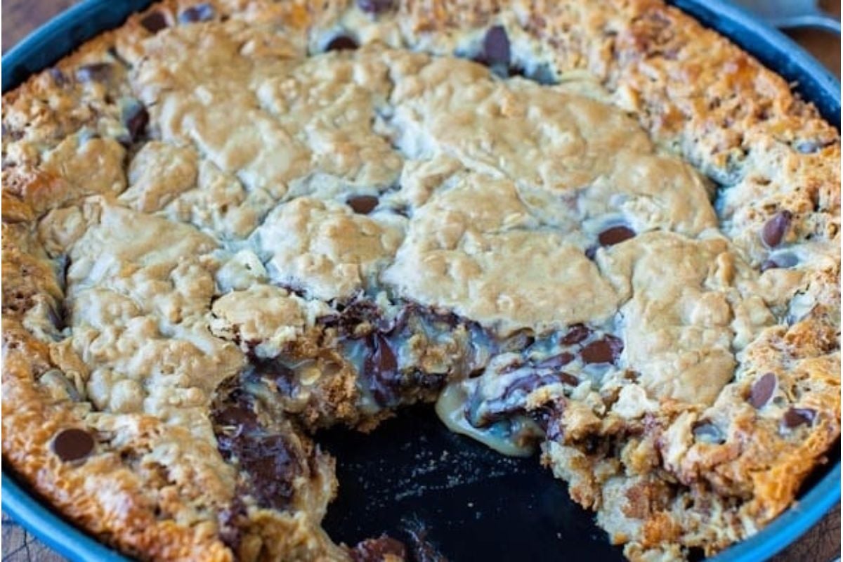 Chocolate peanut butter chip cookie in a skillet with a bite taken out of it.