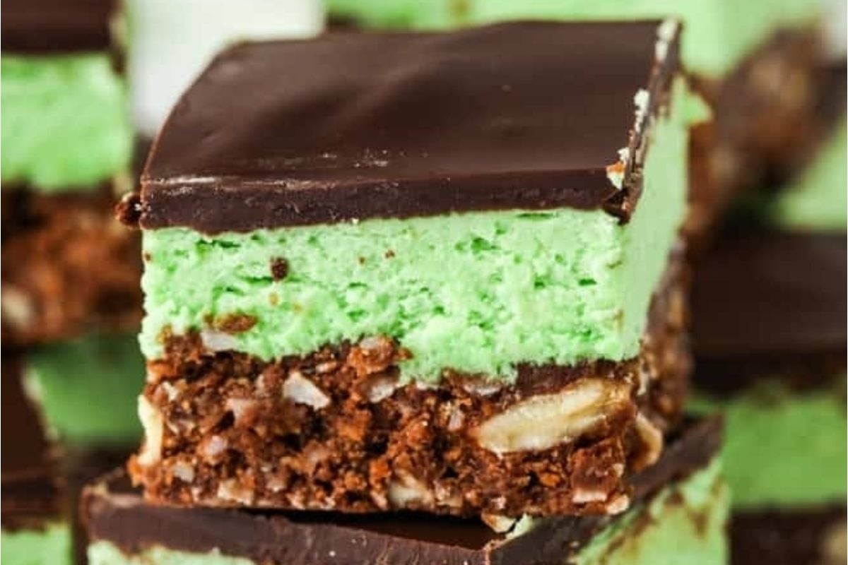 These decadent fudge bars made with chocolate and mint are stacked on top of each other.