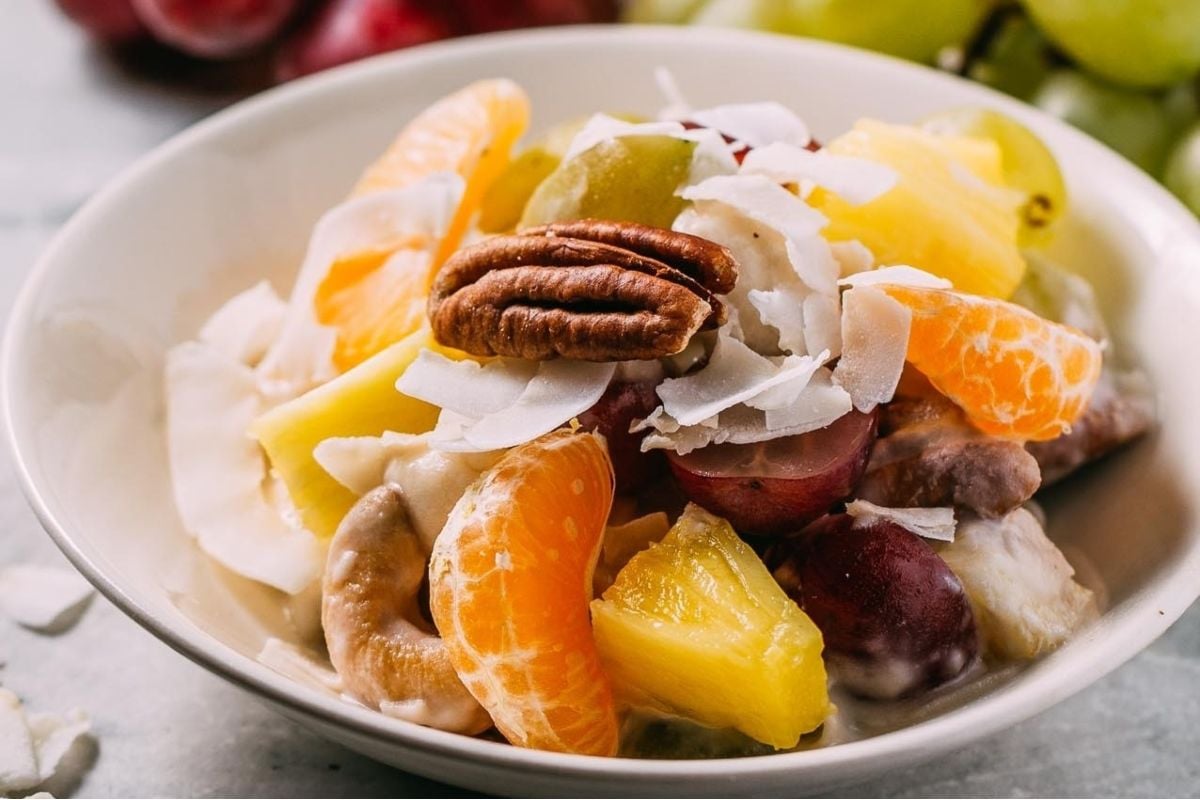 A bowl of fruit salad with grapes, nuts, and citrus fruits.