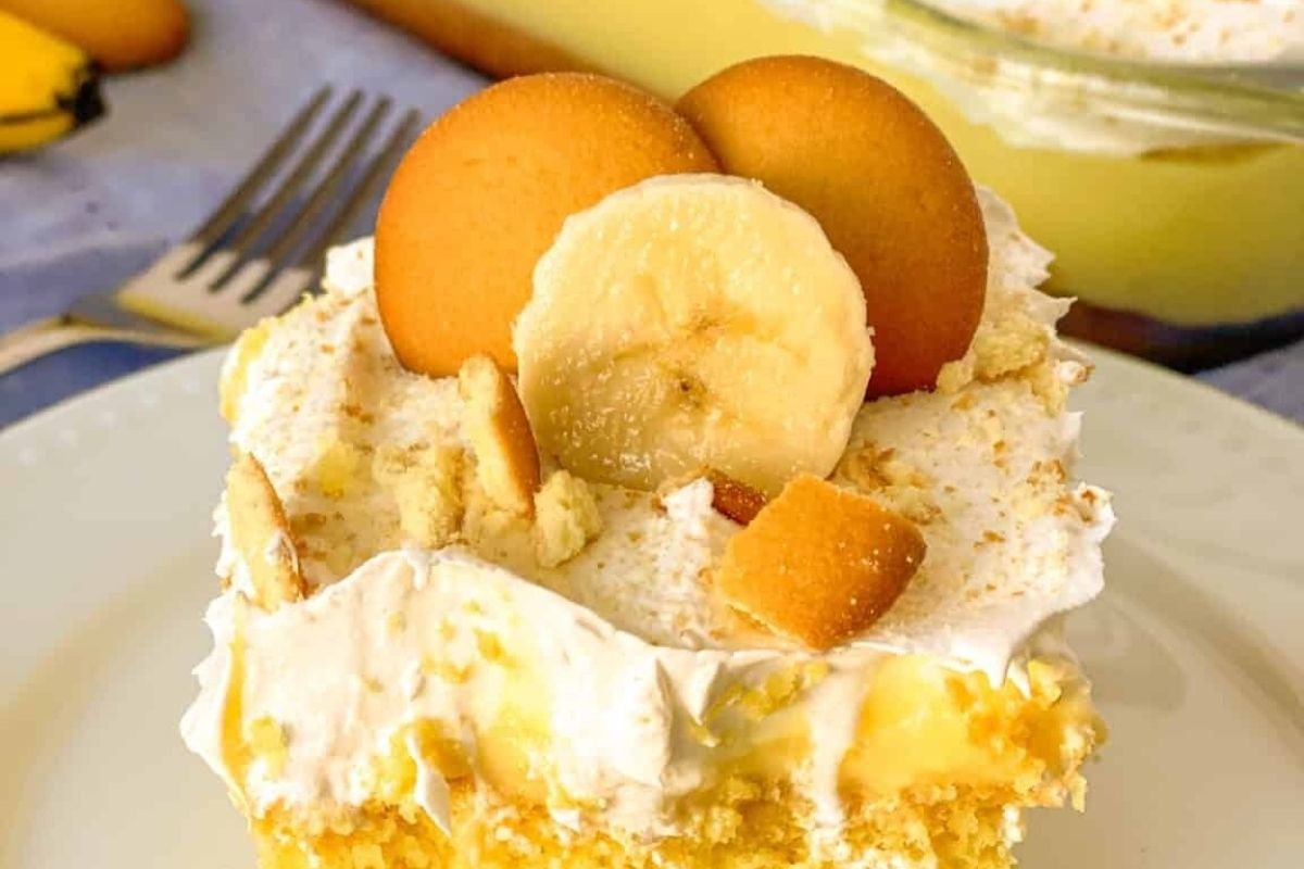 A slice of banana pudding cake topped with Cool Whip on a plate.