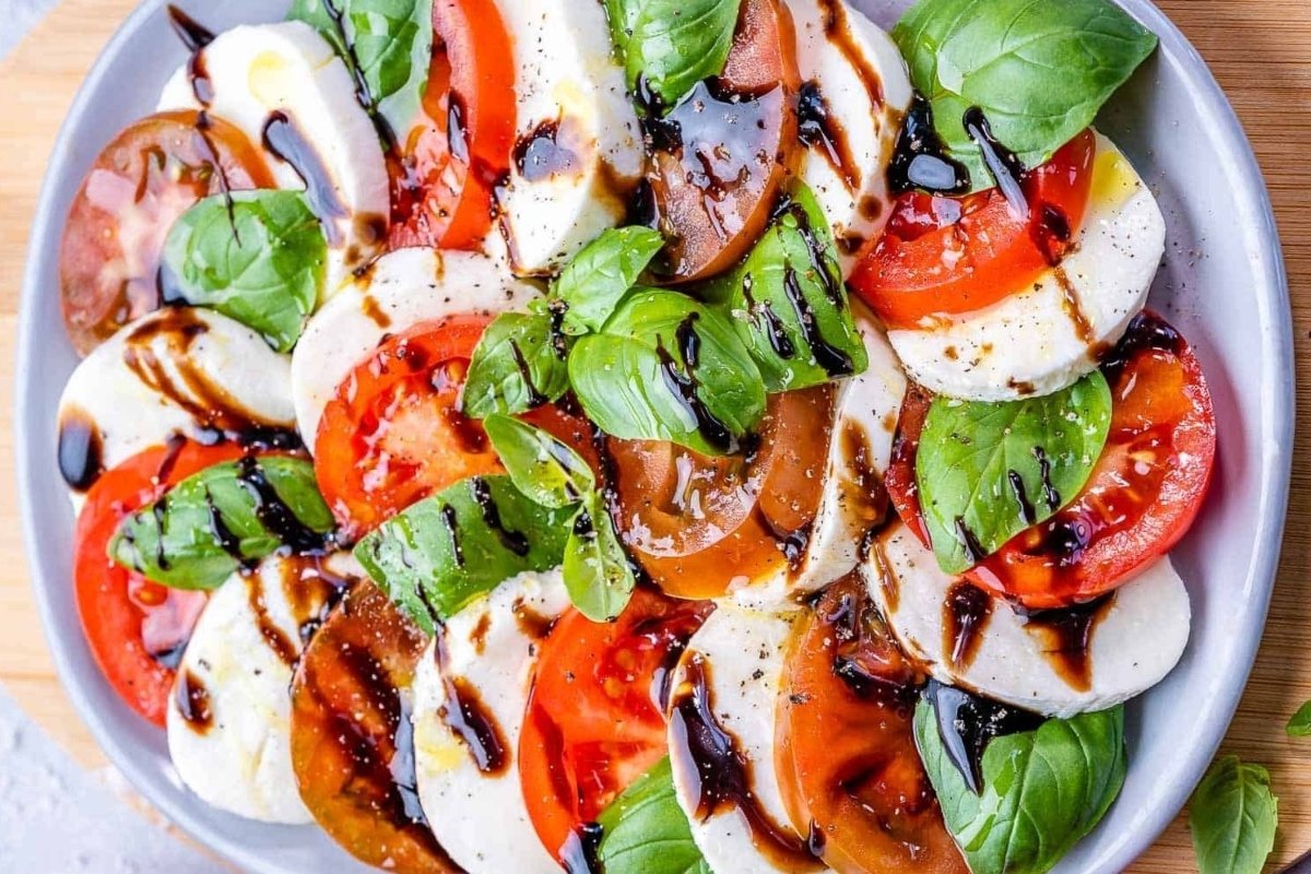 A girl enjoys a plate of tomato and mozzarella salad with balsamic vinaigrette for dinner.