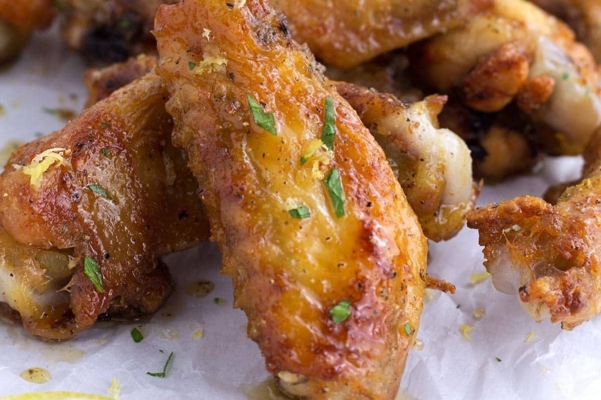 Close-up of crispy, bite-size baked chicken wings—perfect for game day—garnished with chopped herbs and a sprinkle of lemon zest.