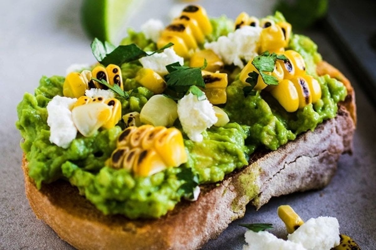 Grilled corn and guacamole on toasted bread for girl's dinner.