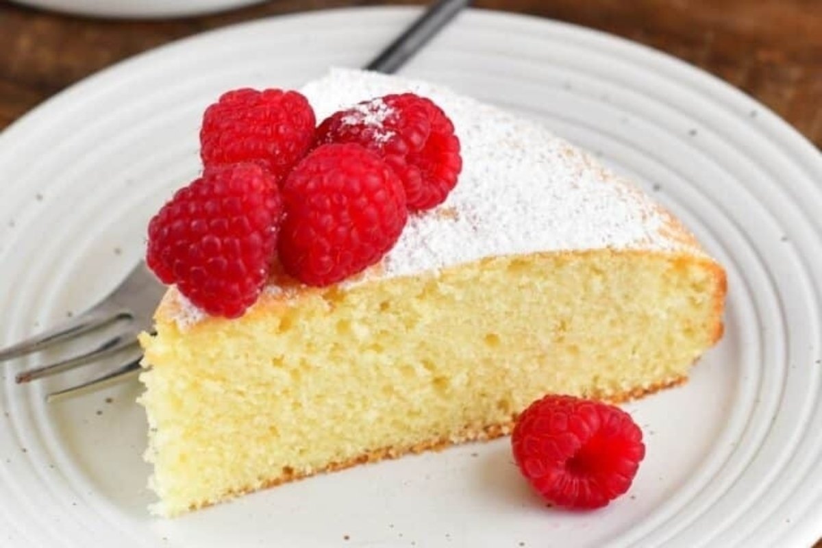 A slice of lemon cake with raspberries on a plate, perfect for St. Patrick's treats.