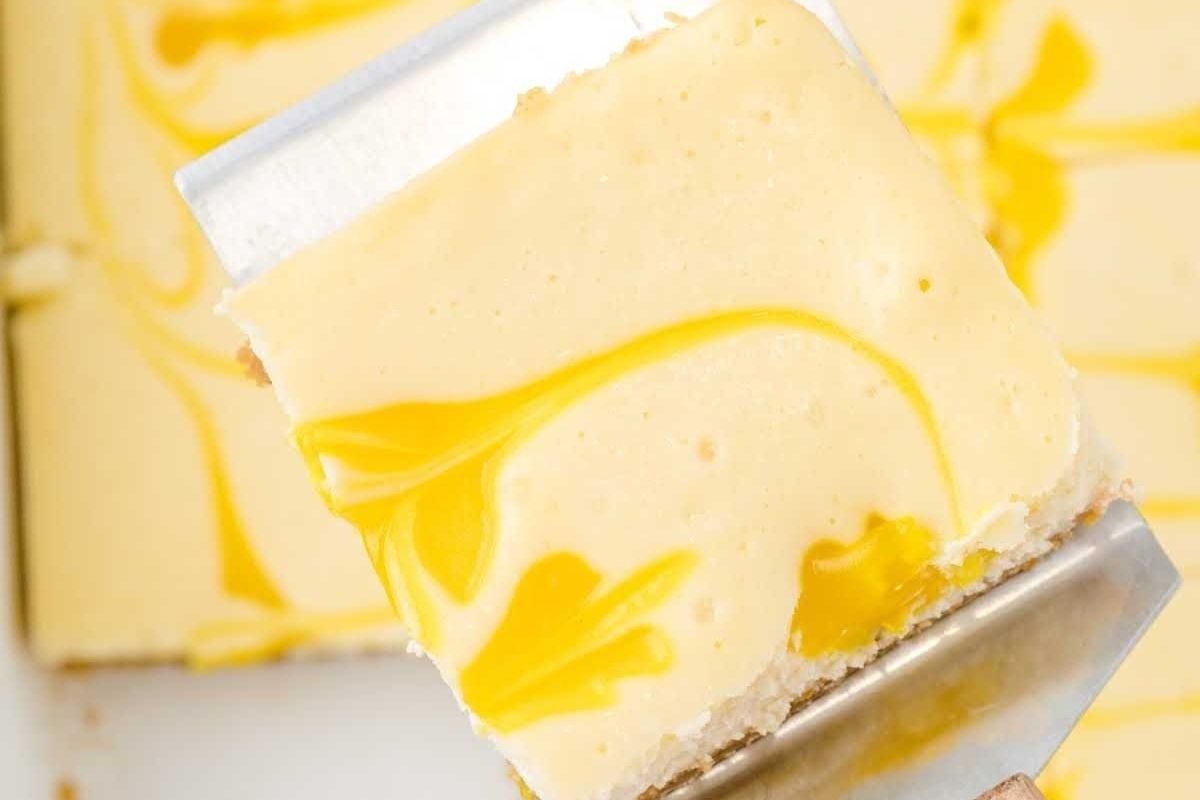 A slice of lemon cheesecake being removed from a pan, perfect for citrus lovers.
