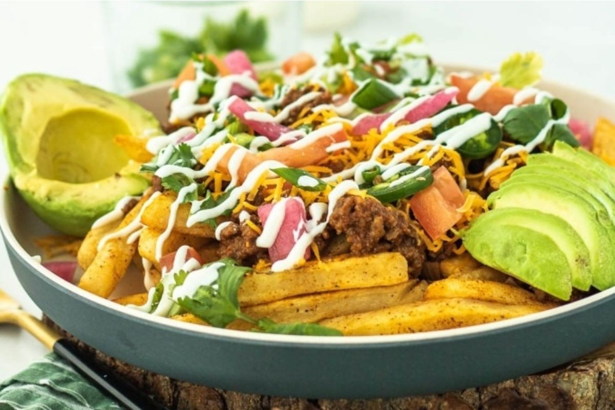 Mexican nachos in a bowl with guacamole and taco flavored avocado.