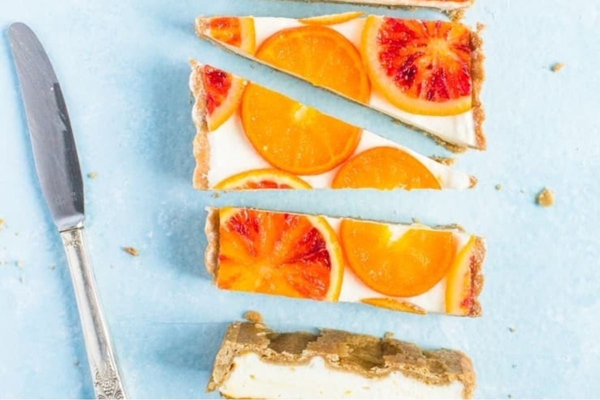 A blood orange tart ready to be devoured with a knife and fork.