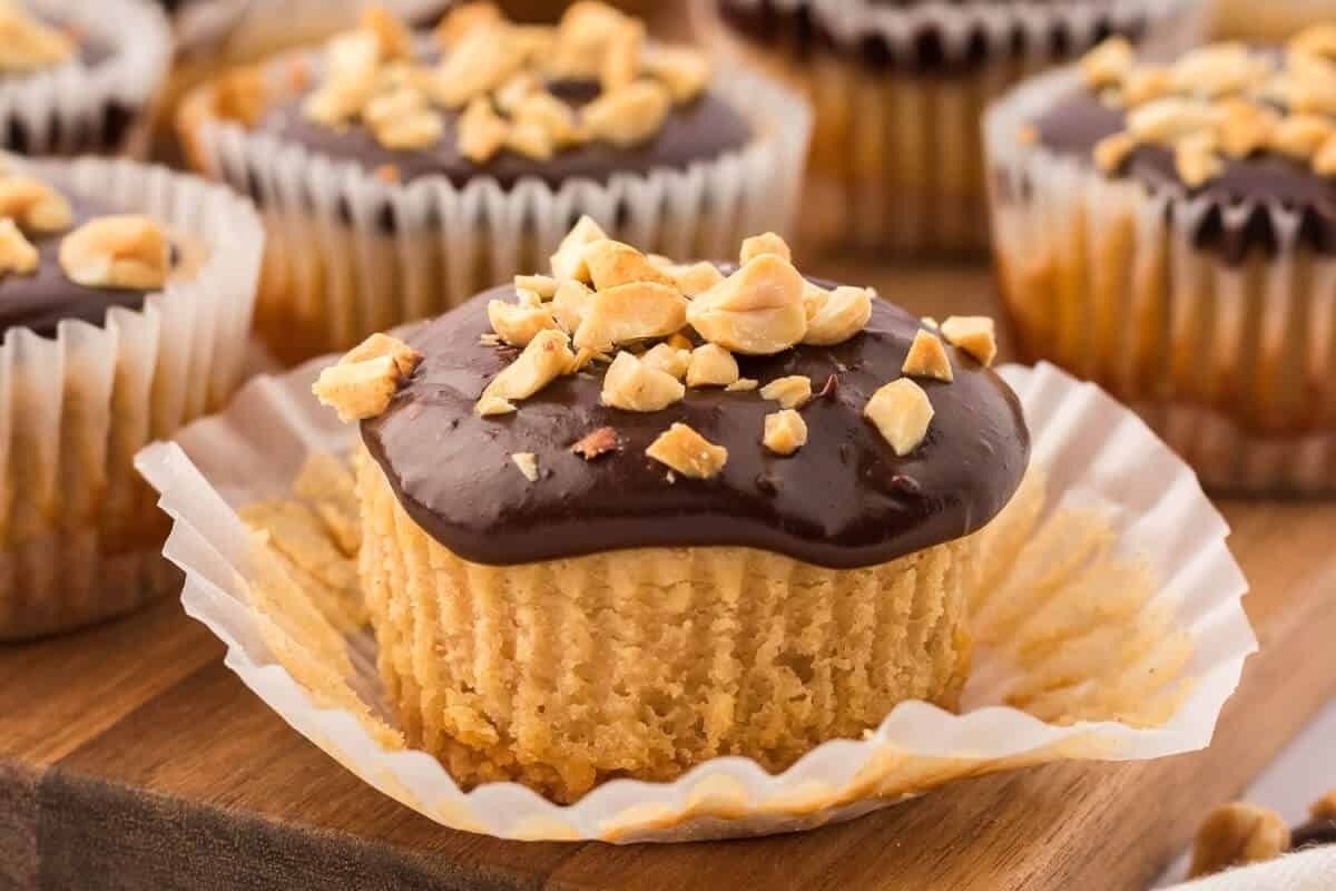 Chocolate peanut butter cupcakes on a wooden cutting board.