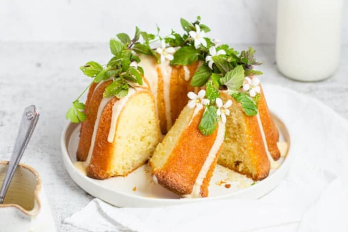 A citrus bundt cake on a plate with a slice taken out.