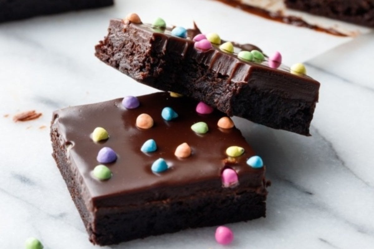 A slice of chocolate brownie with rainbow sprinkles.