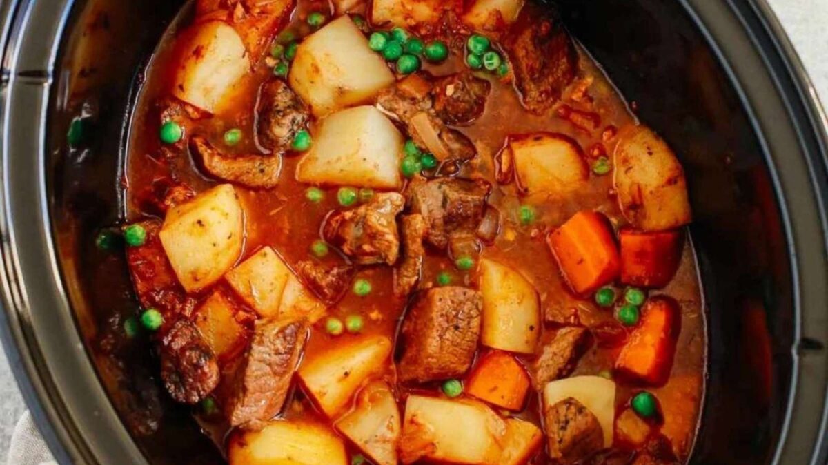 A hearty slow cooker beef stew with potatoes, carrots, peas, and chunks of beef in a rich broth—perfect for any shared roundup or cozy family meal.