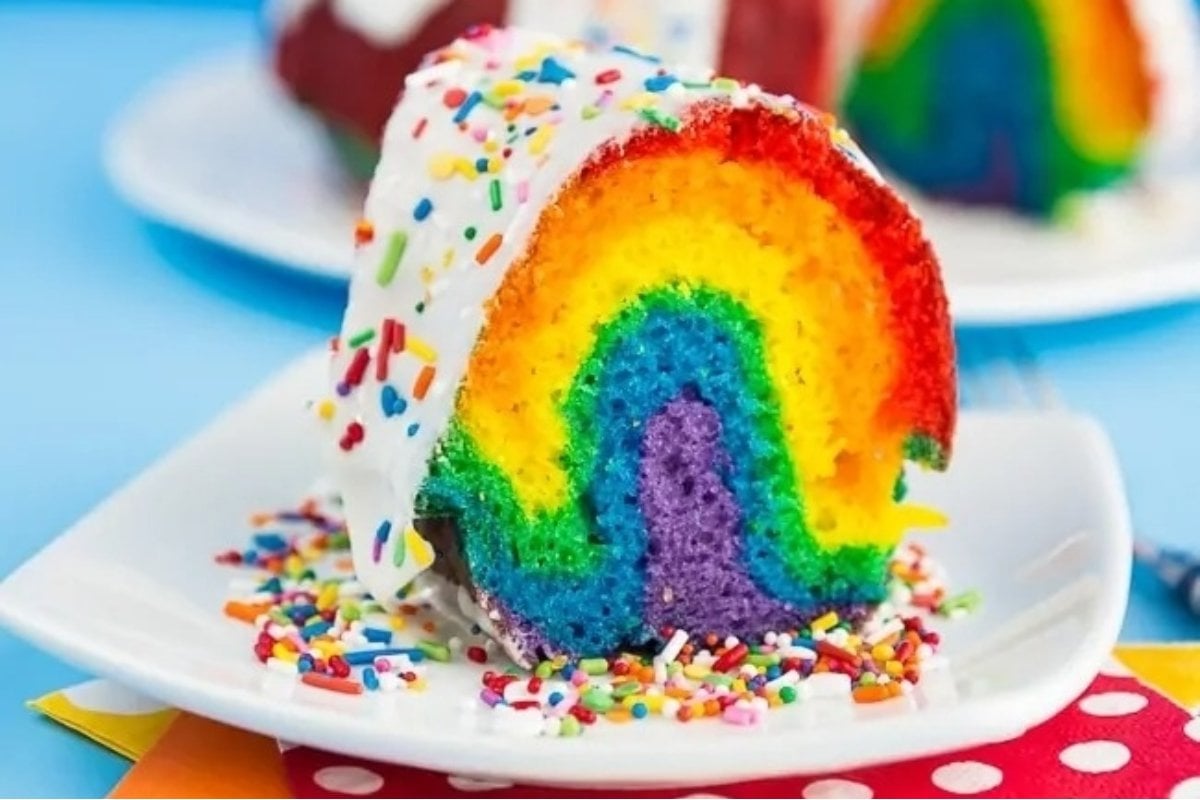 A rainbow cake with sprinkles on a plate is a colorful treat that will delight any party guest.