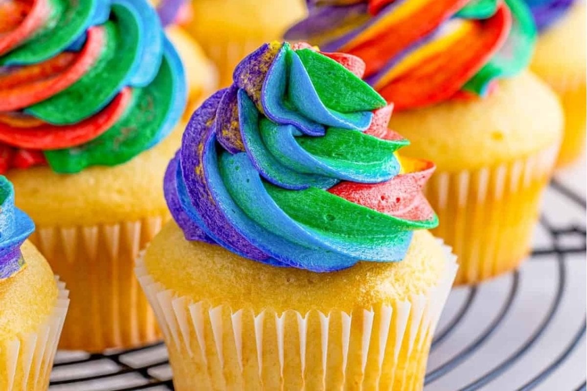 A close up of a cupcake with rainbow frosting.