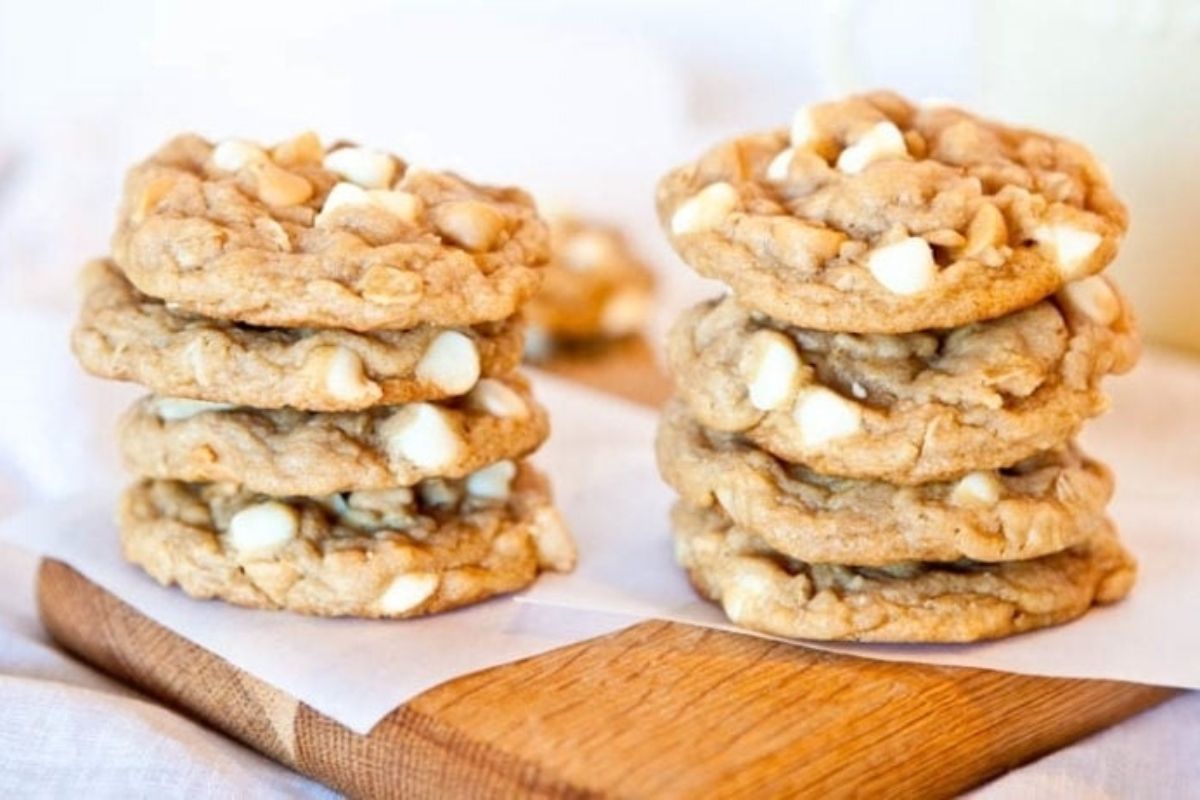 A stack of white chocolate peanut butter chip cookies on a cutting board.