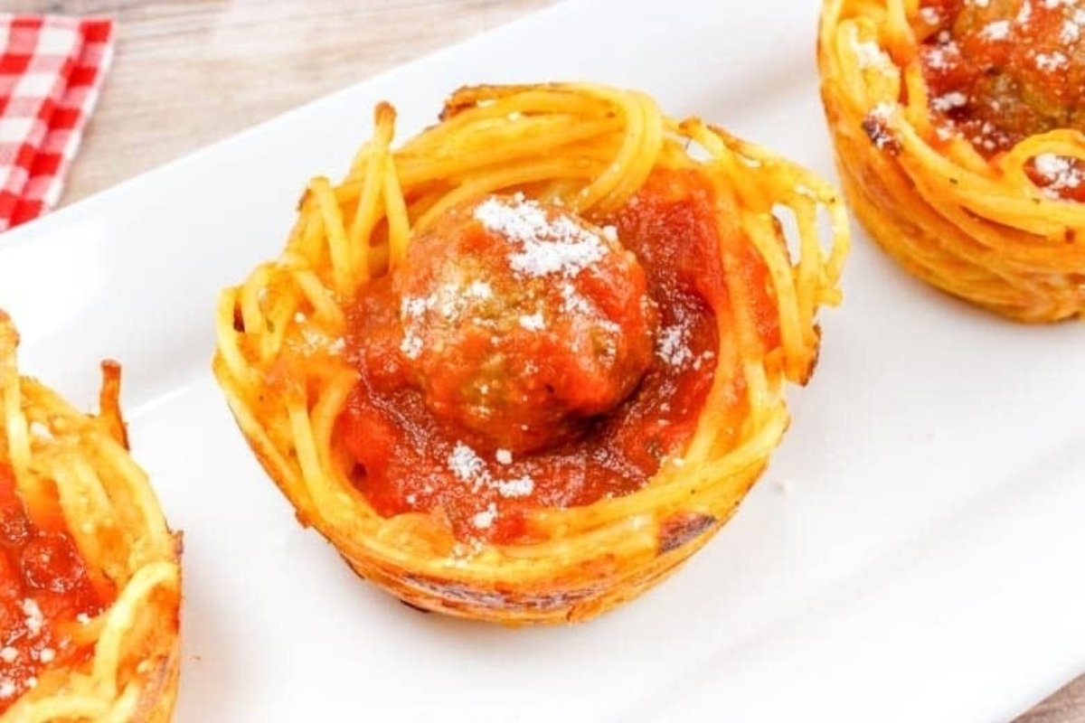 Plate of spaghetti nests topped with meatballs and marinara sauce, garnished with grated parmesan cheese, perfect as bites for dinner.