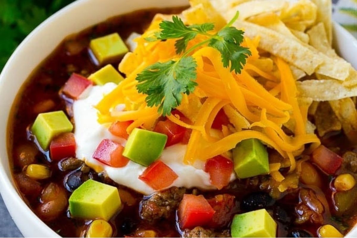 A bowl of taco-flavored chili with tortilla chips and sour cream.