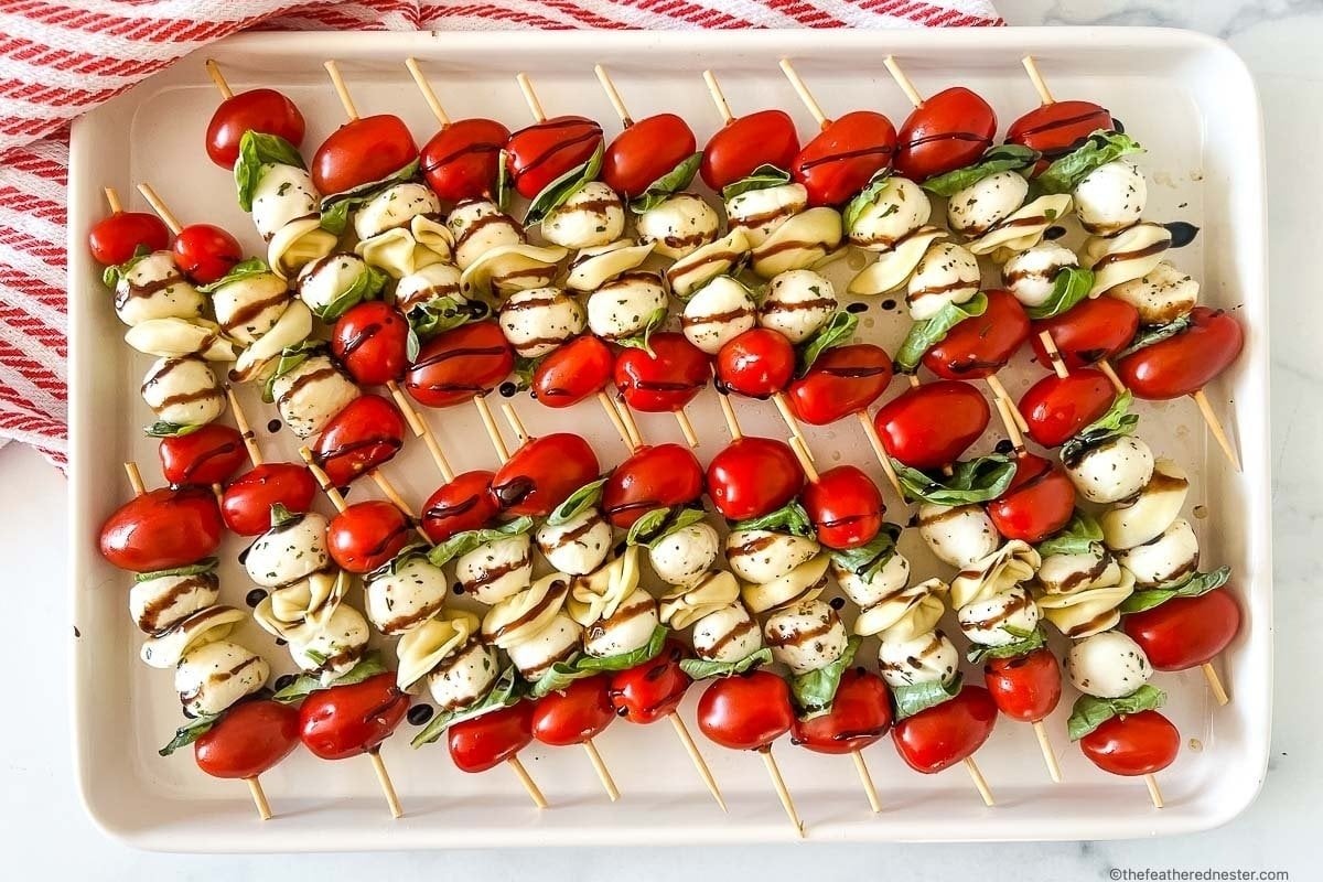 Tomatoes and mozzarella skewers on a white plate for girl's dinner.