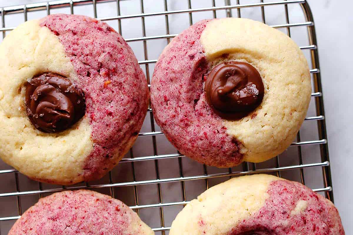 Two-tone thumbprint Valentine's Day cookies with a chocolate center resting on a wire cooling rack.
