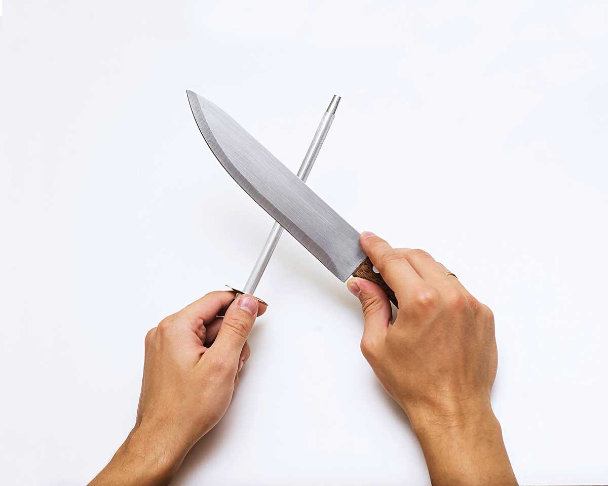 Knife sharpening with whetstone sharpener or grindstone, The abrasive which sharpen the knife blade, man using a knife grinder, man hand sharpenes knife on white background