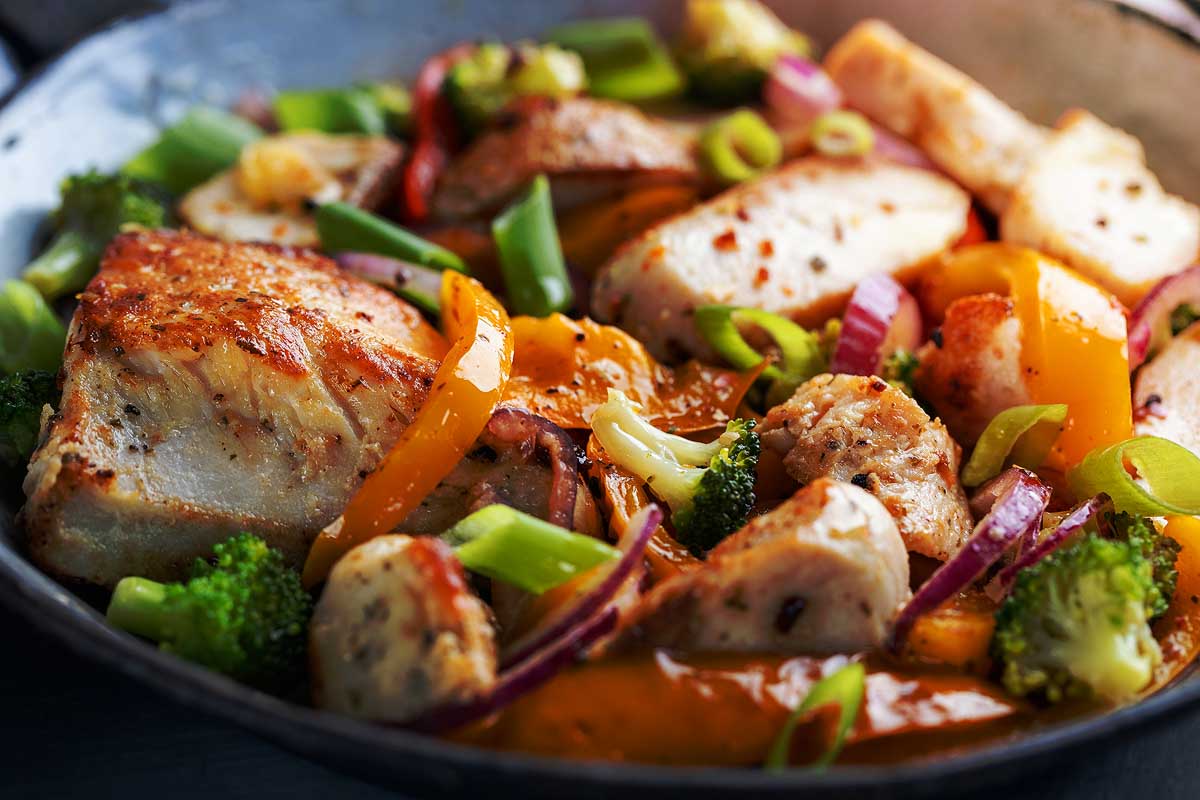Chicken and vegetables fried or stuffed served on pan on bright background.