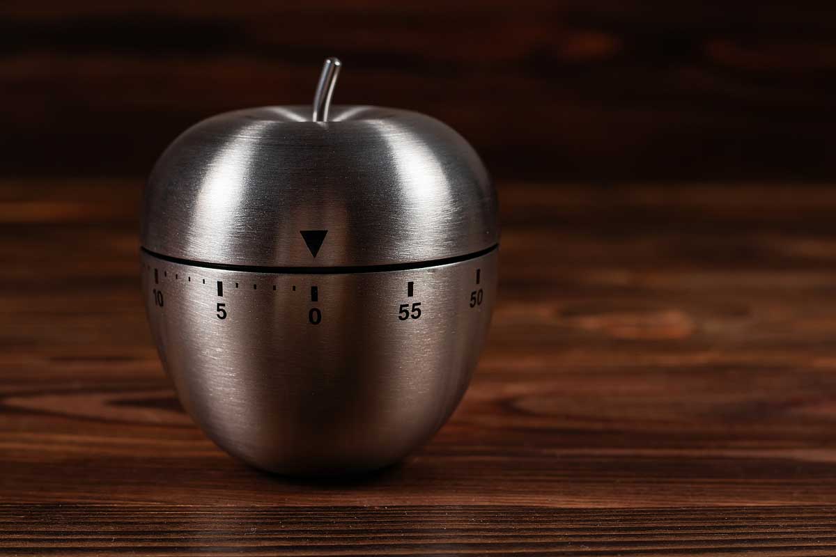 Metal apple kitchen timer on wooden background.