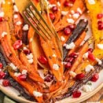 A plate of roasted multi-color carrots with a fork and a spoon.