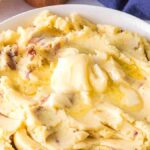 Red skin mashed potatoes in a white bowl with butter.