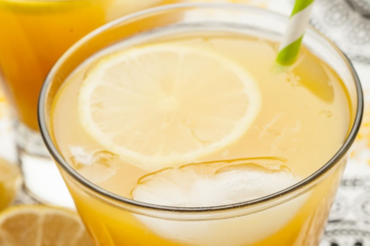A close-up of a glass of iced lemonade, an ideal Easter cocktail, with a straw and lemon slice.