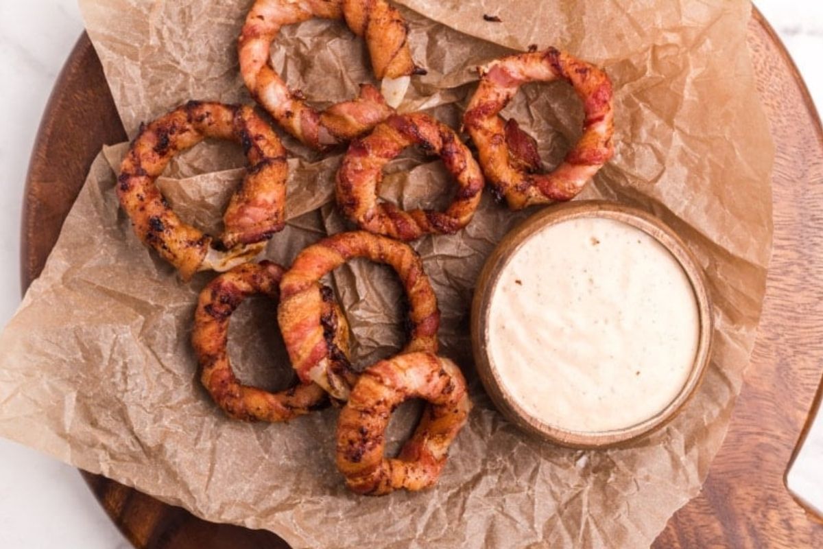 Grilled shrimp served with a side of dipping sauce on a wooden plate for Father's Day breakfast.