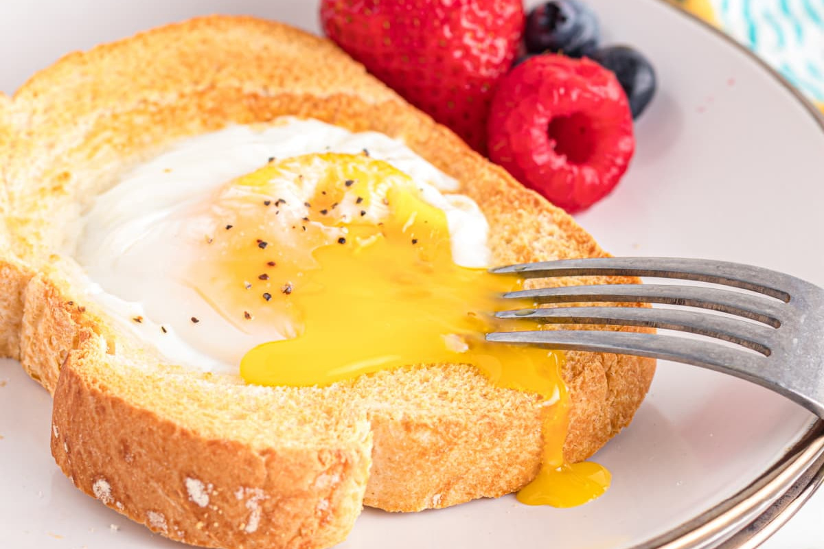 Air Fryer Eggs On Toast with fork on white plate.