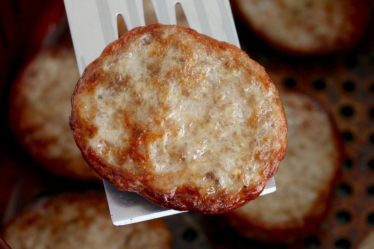 A cooked sausage patty being lifted with a white plastic fork for Father's Day breakfast.