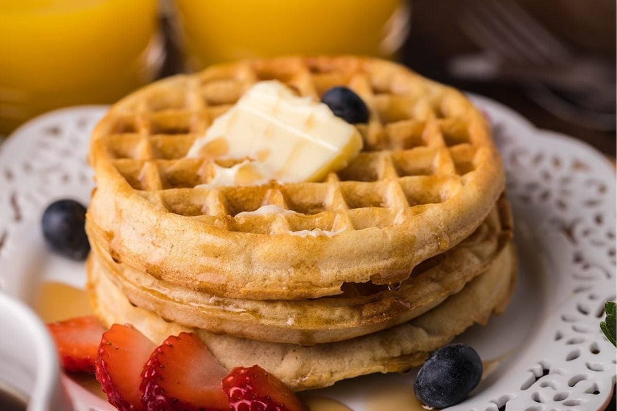 Stack of waffles with butter and berries on a plate, perfect for air fryer breakfast recipes.