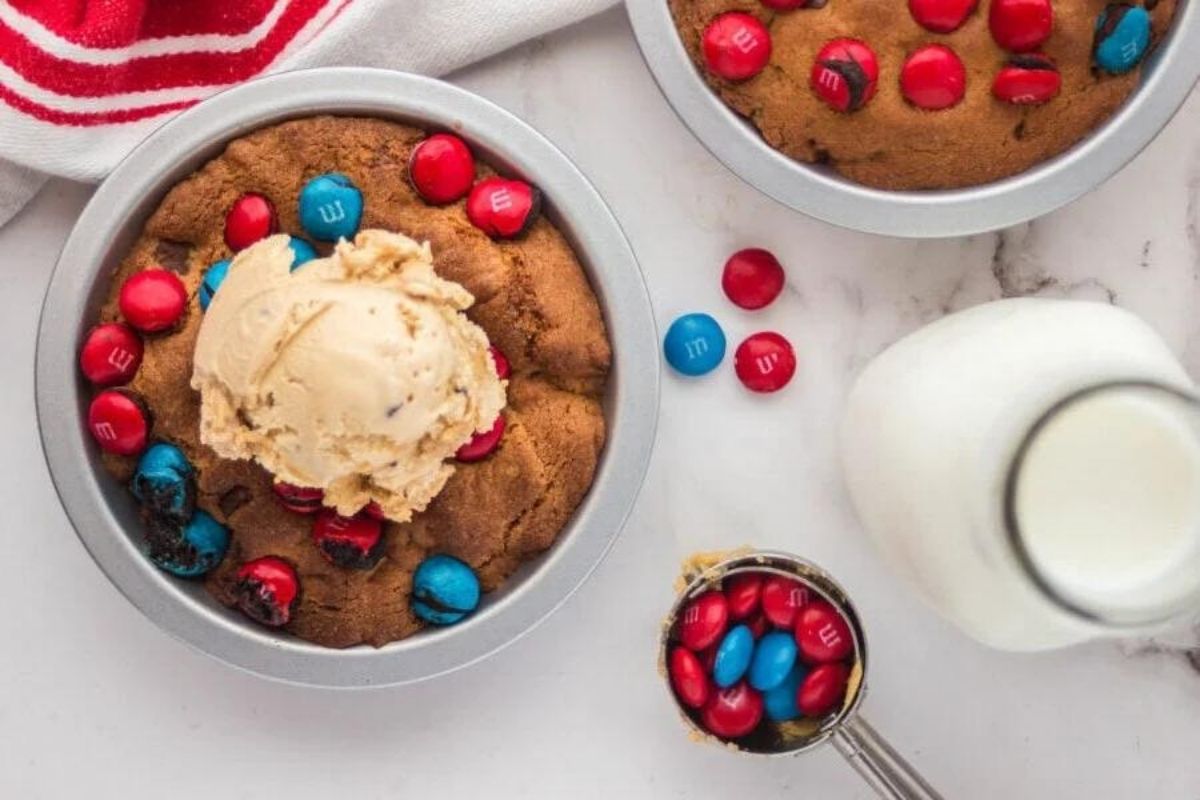 Freshly baked cookie in a skillet topped with vanilla ice cream and m&m's, accompanied by a glass of milk - the perfect Father's Day breakfast.