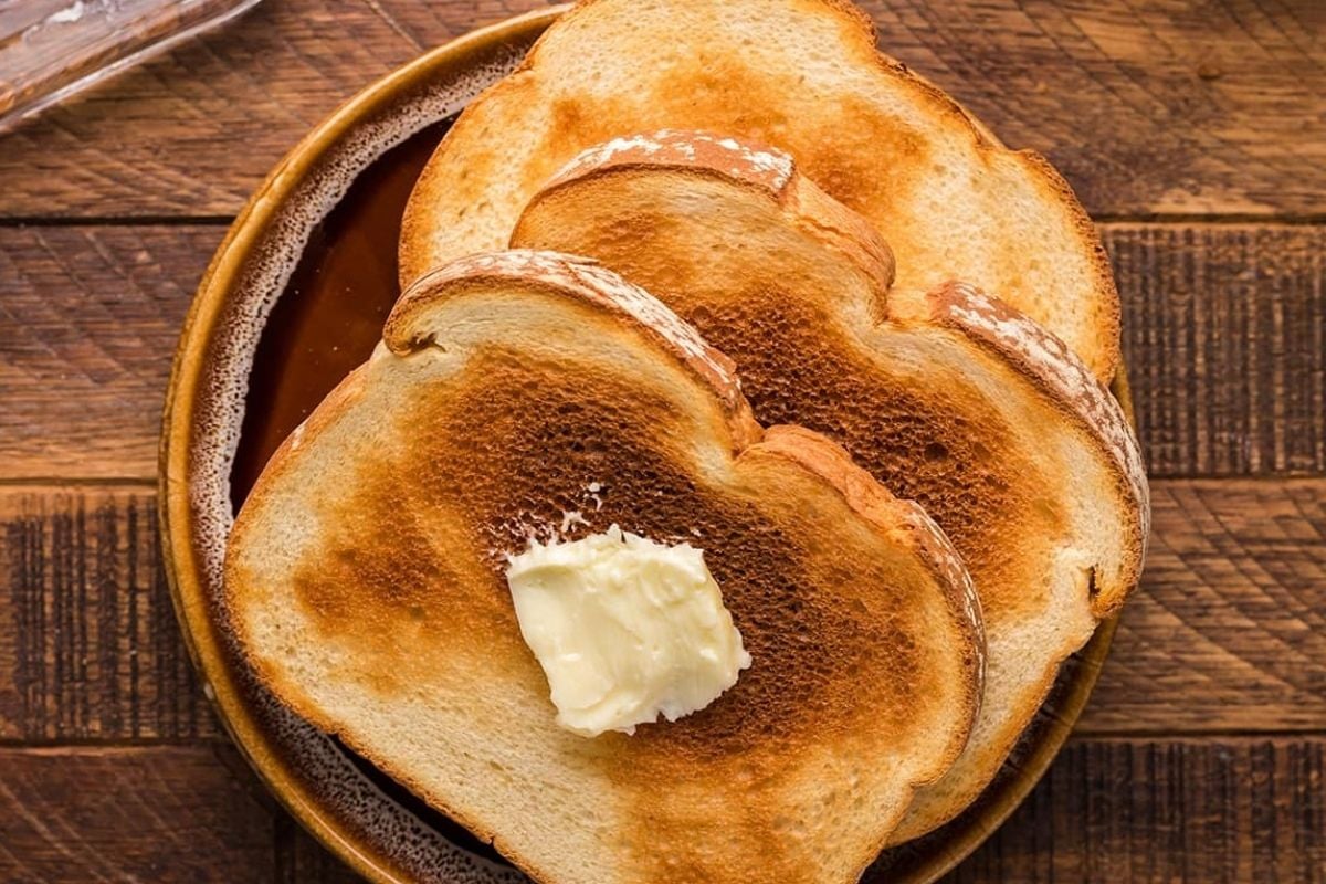 Slices of toasted bread made in an air fryer with a pat of butter on a plate, perfect for breakfast.