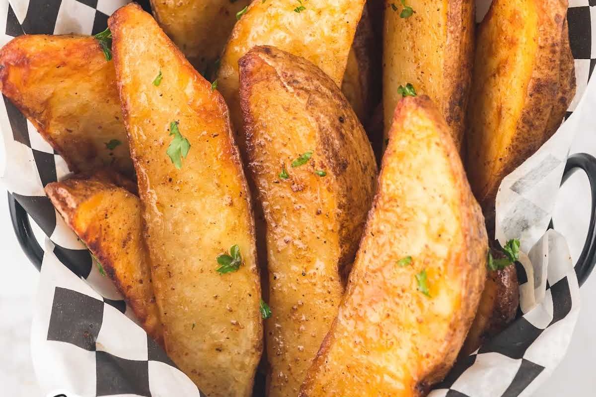 Golden potato wedges seasoned with herbs, served as Easter sides in a striped container.