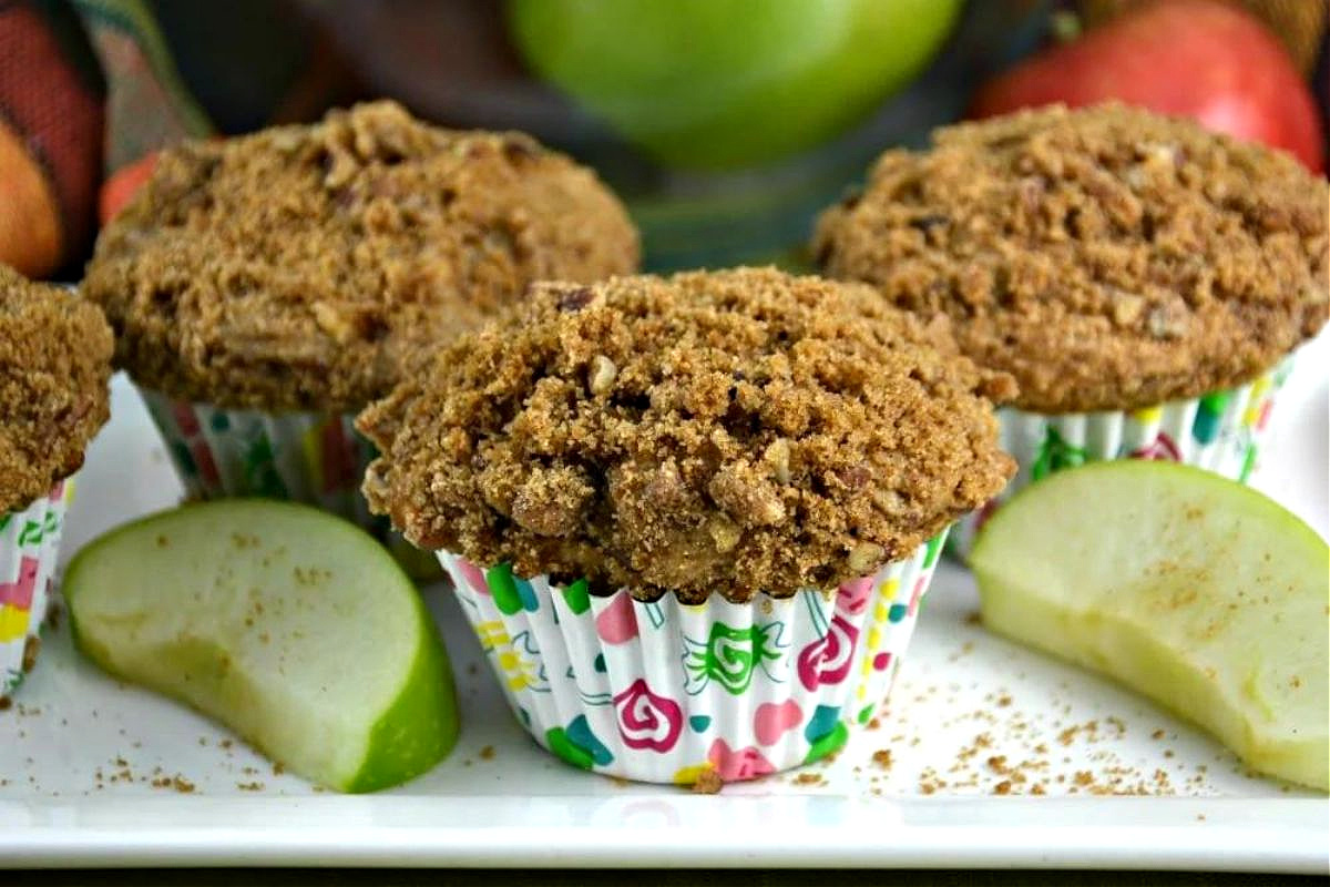 Freshly baked muffins with a crumbly topping, surrounded by apples, perfect for pie recipes.