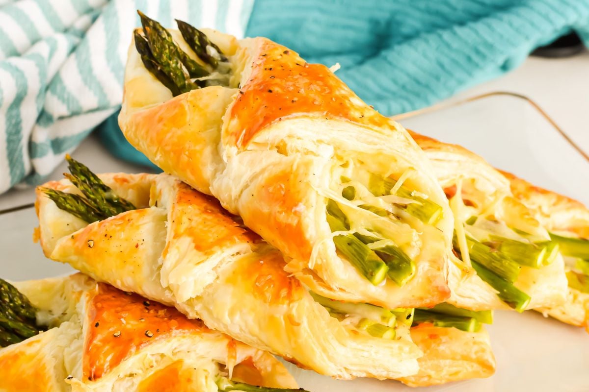 Freshly baked asparagus pastry twists on a white surface, perfect as an Easter appetizer.