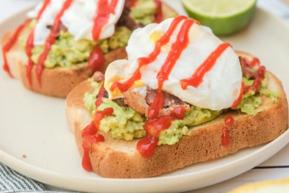 Two toasts with guacamole, ketchup, and egg recipes on a plate.