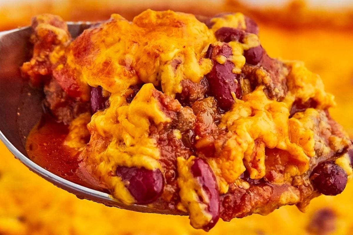A close-up of a spoonful of cheesy chili with beans, ground meat, and melted cheddar cheese—perfect for fans of comforting cheesy recipes.