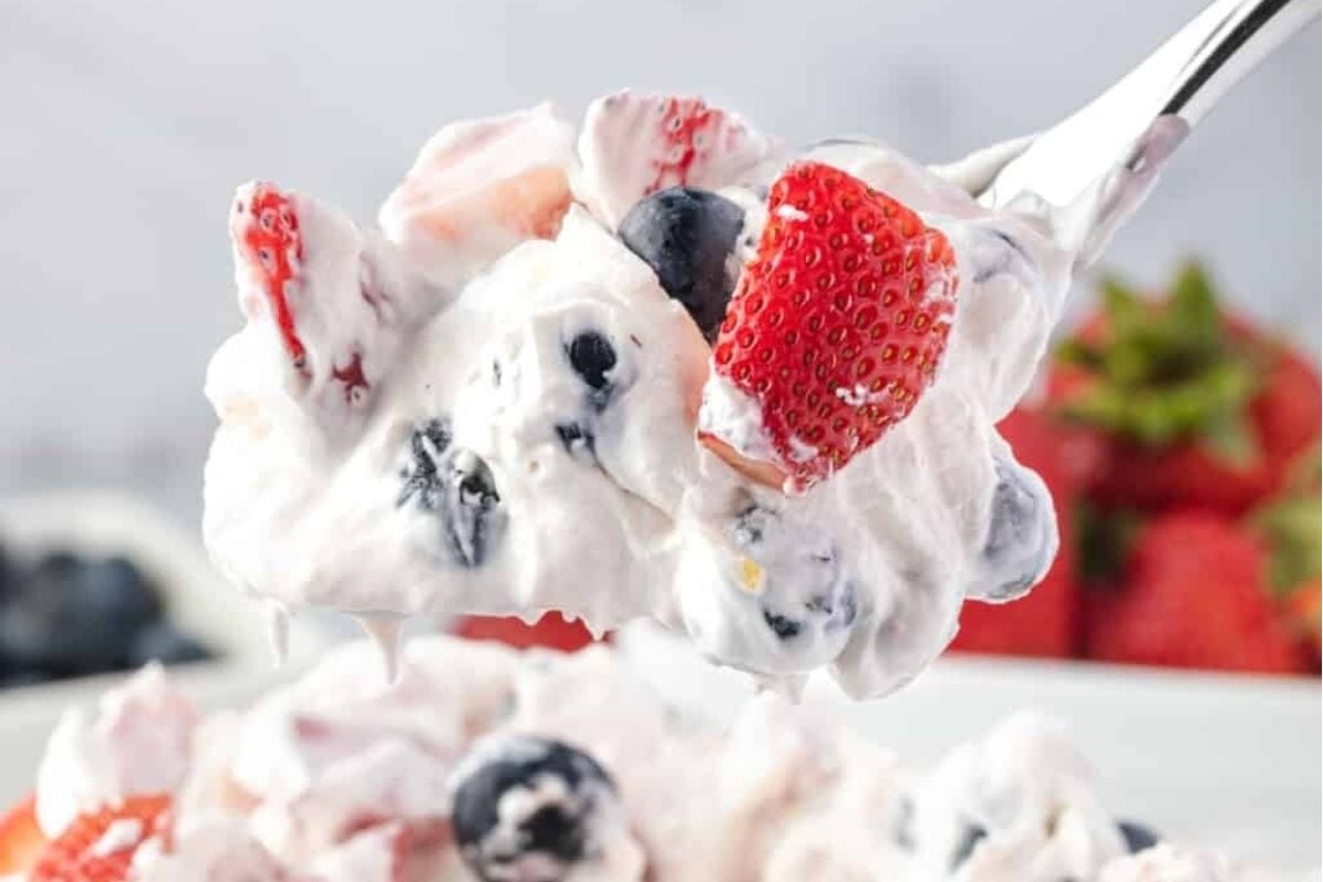 A fork is being used to scoop up a bowl of potluck berry salads.