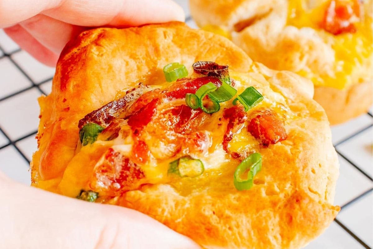 A person holding up a bacon, egg, and cheese biscuit.
