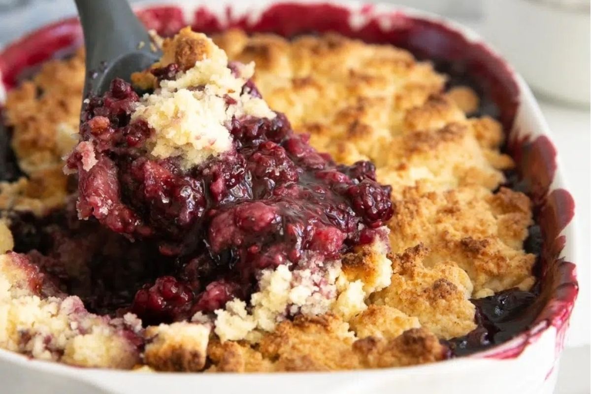 A potluck dish with a scoop of berry cobbler.