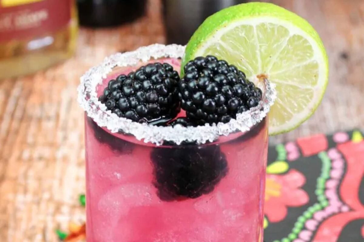A refreshing Easter blackberry cocktail garnished with lime and berries on a salt-rimmed glass.