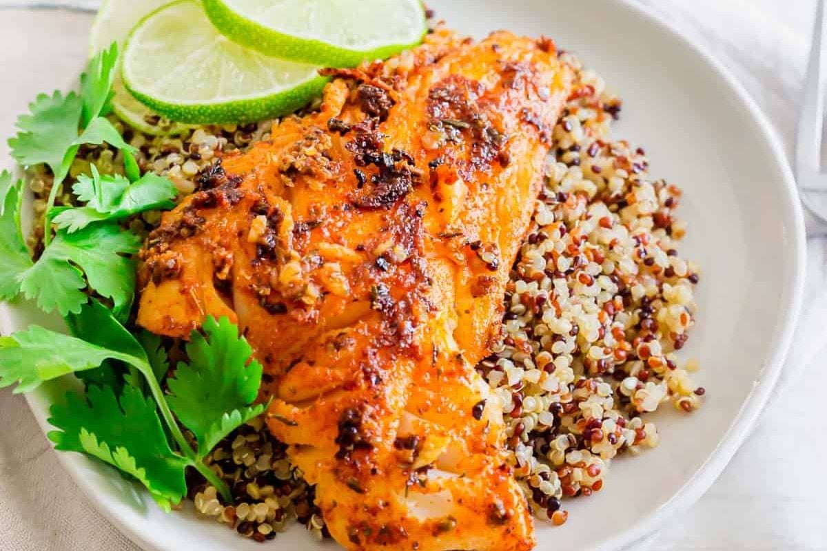 Grilled fish fillet on quinoa with lime slices and fresh cilantro makes a vibrant addition to your collection of seafood recipes.