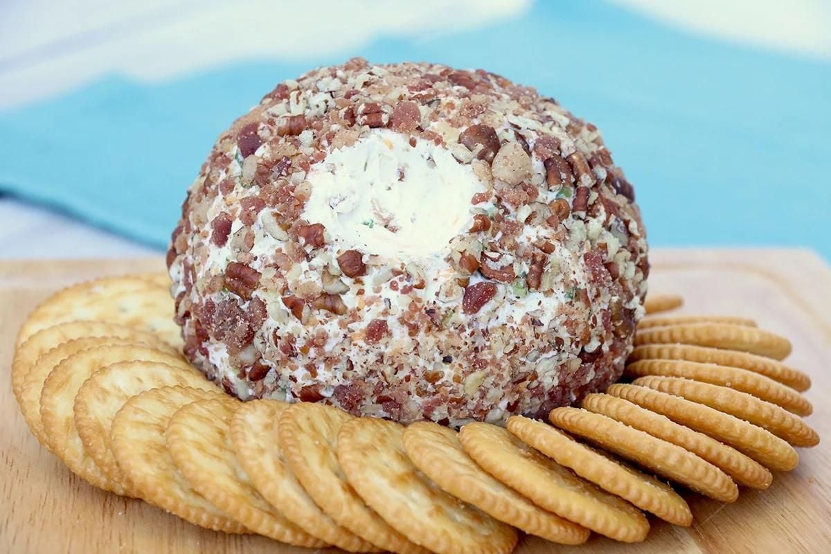 A cheese ball topped with bacon and crackers.