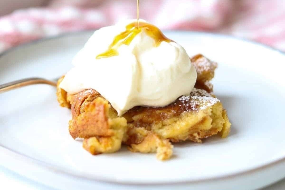A slice of spring bread pudding with whipped cream on a plate.